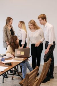 Une équipe diversifiée de jeunes professionnels engagés dans une réunion collaborative autour d'un ordinateur portable dans un environnement de bureau moderne.