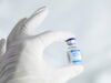 Main gantée tenant une petite bouteille de vaccin
