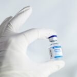 Main gantée tenant une petite bouteille de vaccin