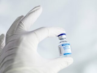 Main gantée tenant une petite bouteille de vaccin