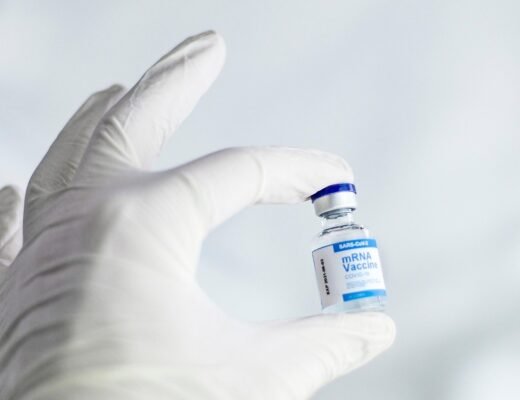 Main gantée tenant une petite bouteille de vaccin