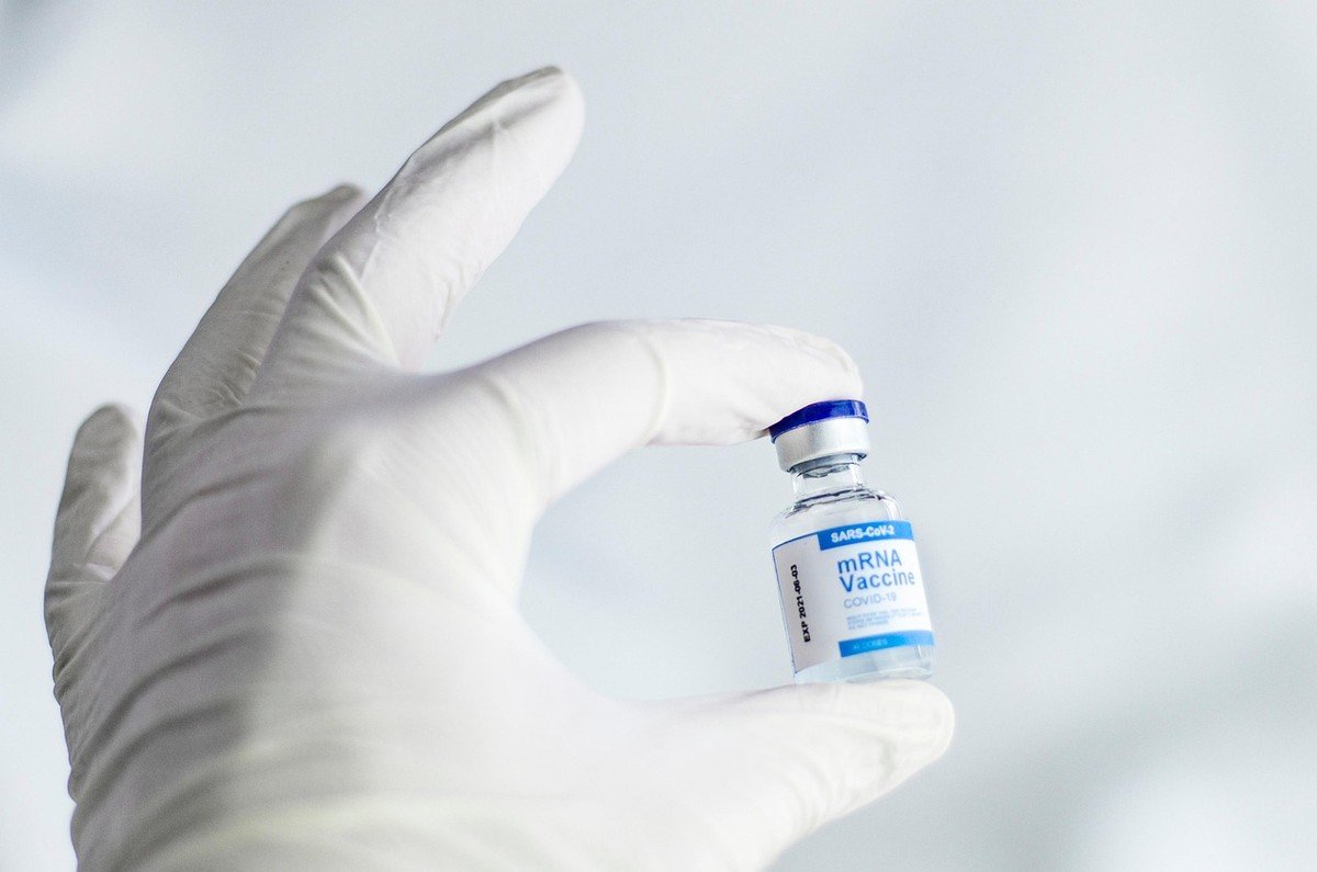 Main gantée tenant une petite bouteille de vaccin