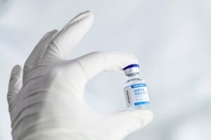 Main gantée tenant une petite bouteille de vaccin