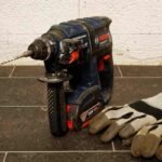 Perceuse et gants de travail sur un sol en carrelage