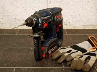 Perceuse et gants de travail sur un sol en carrelage