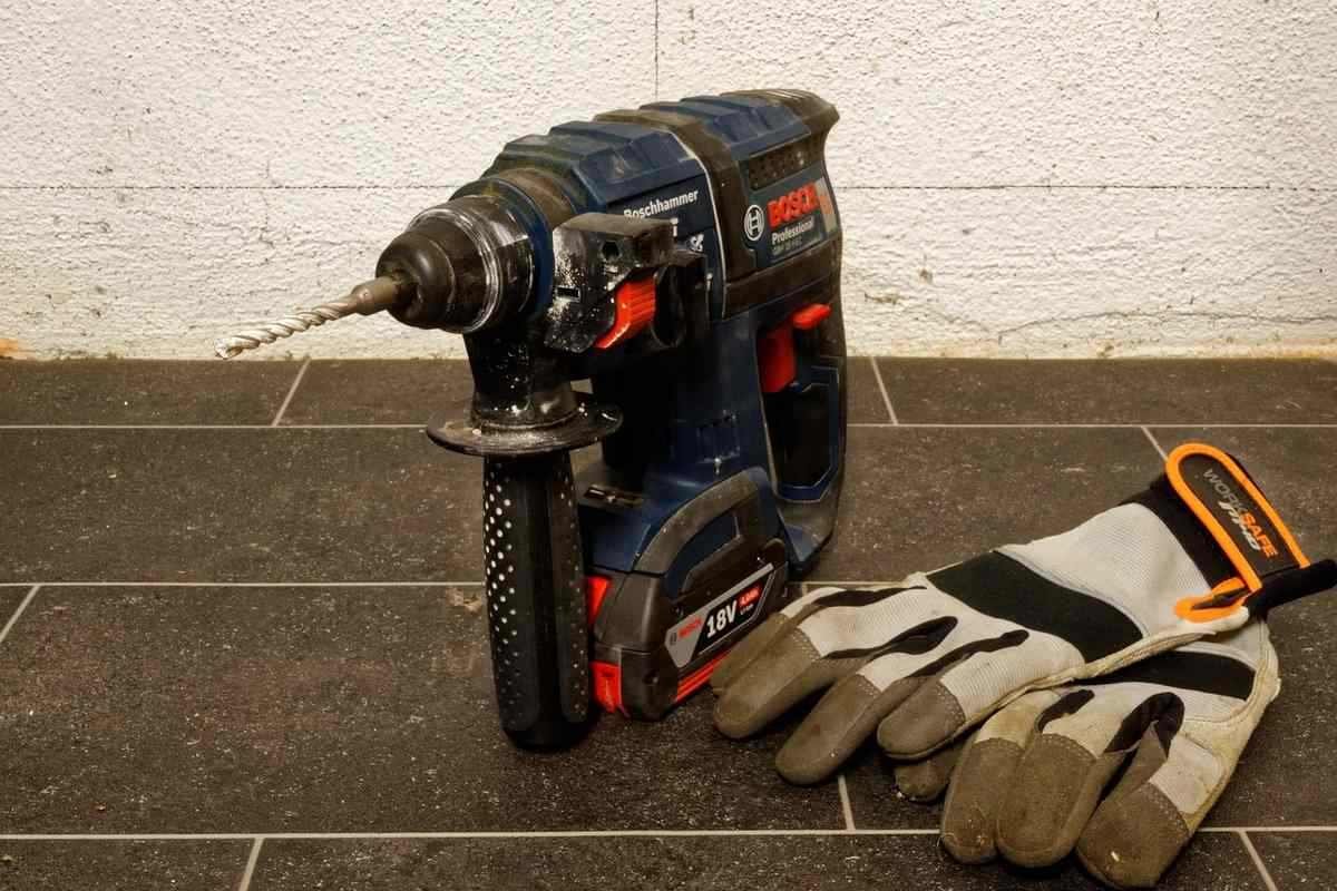 Perceuse et gants de travail sur un sol en carrelage