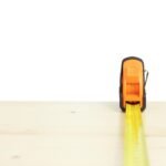 Ruban à mesurer jaune déployé horizontalement sur une surface de bois clair