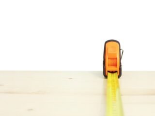 Ruban à mesurer jaune déployé horizontalement sur une surface de bois clair